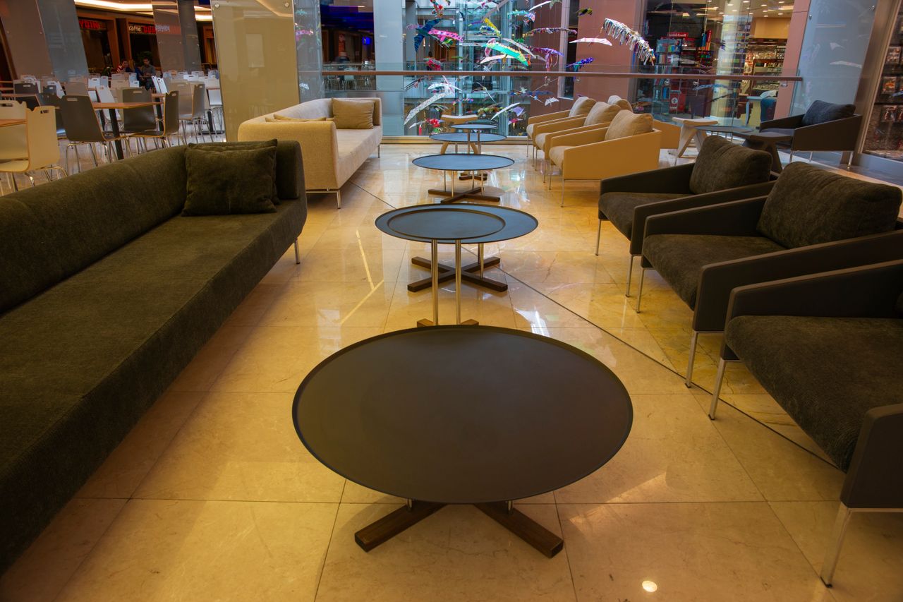 About Contemporary lounge space featuring sleek sofas and round coffee tables in a shopping mall.